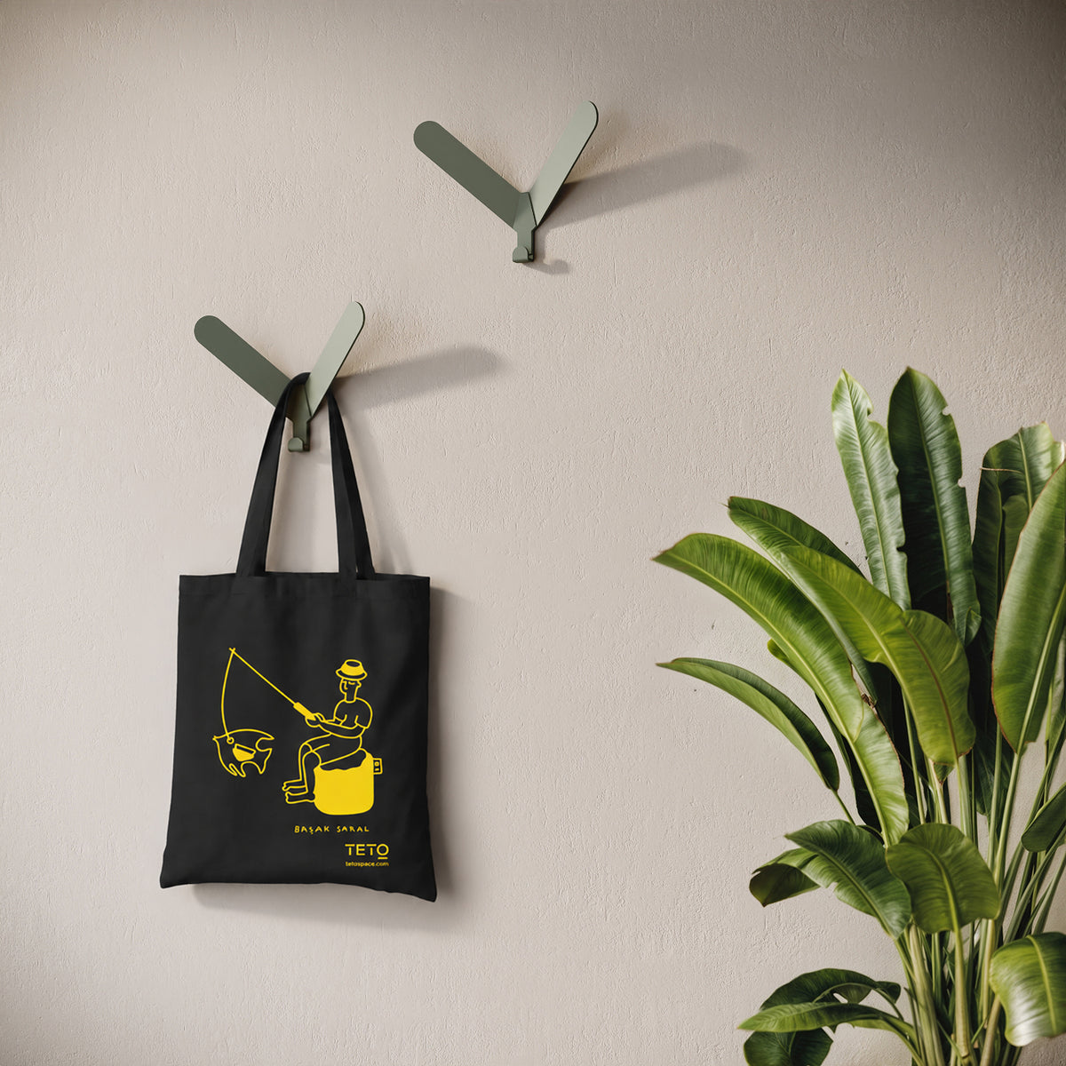 Tote bag in canvas Nero con illustrazione Fish di Başak Saral (pescatore seduto sul pouf), ambientata – TETO