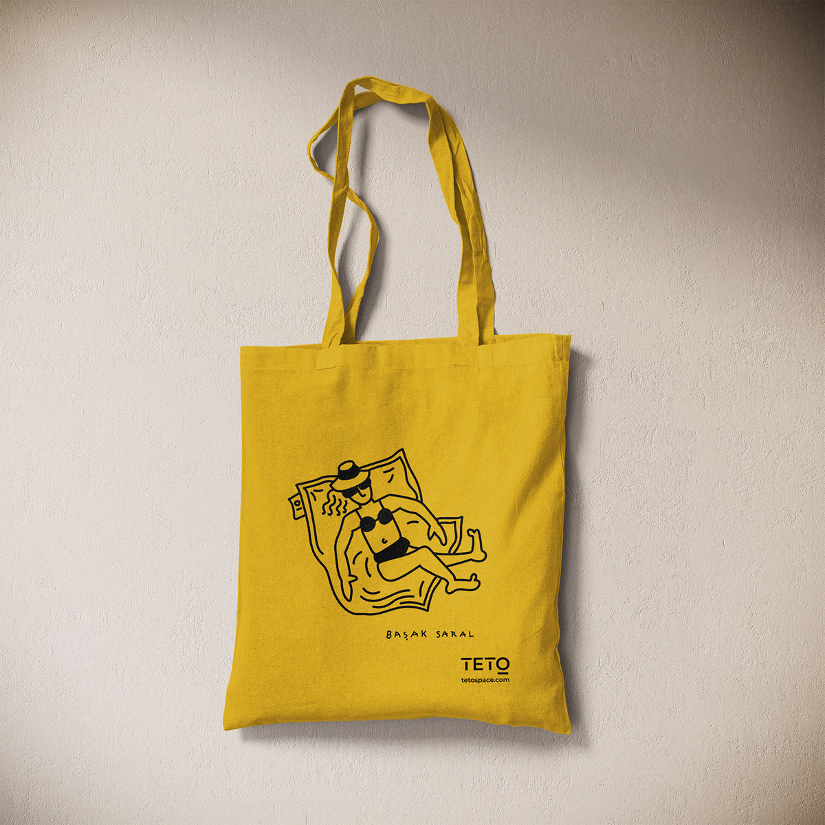 Tote bag in canvas Giallo con illustrazione Pouf di Başak Saral (donna che prende il sole sdraiata sul pouf), vista frontale – TETO