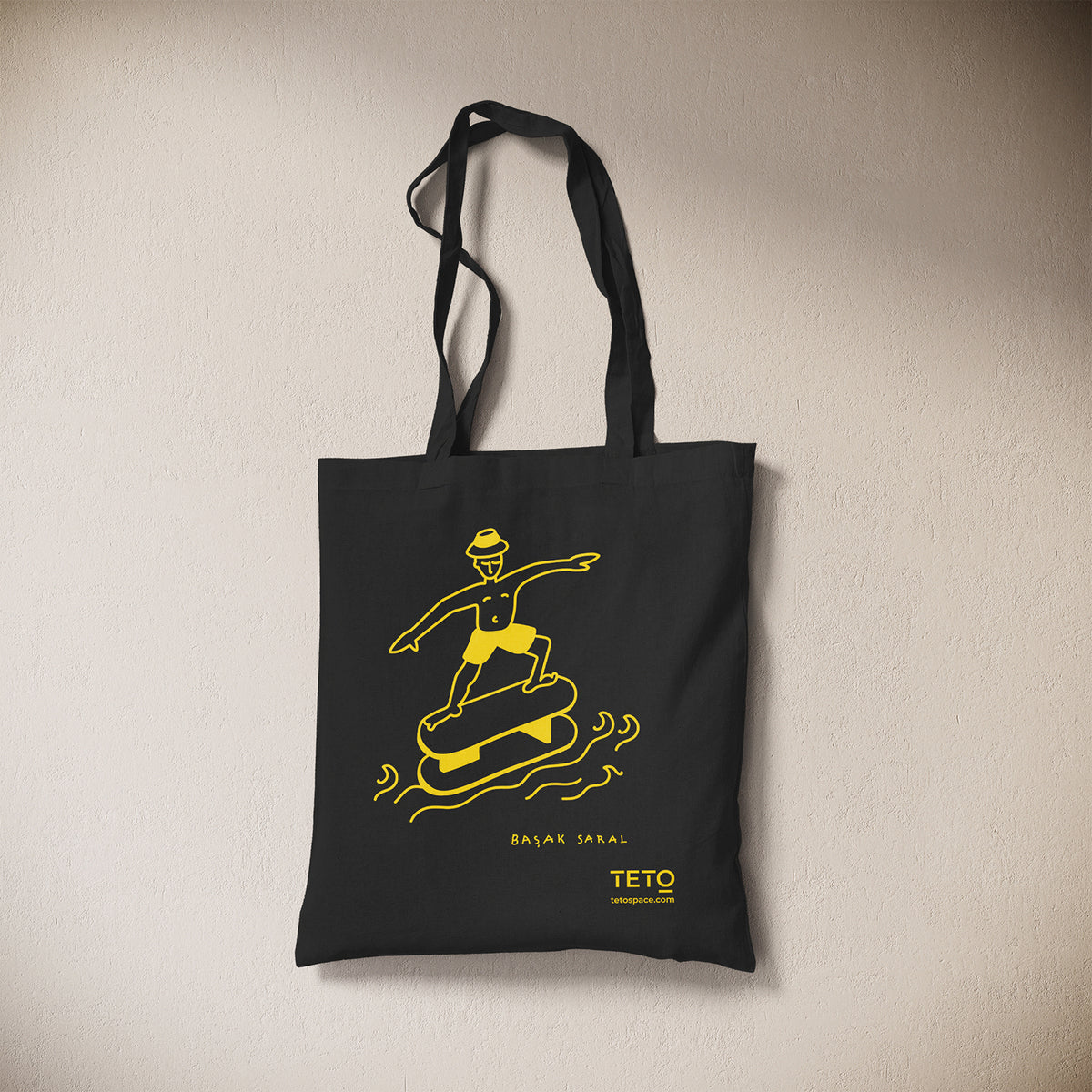 Tote bag in canvas Nero con illustrazione Serf di Başak Saral (surfista sul pouf tra le onde), vista frontale – TETO