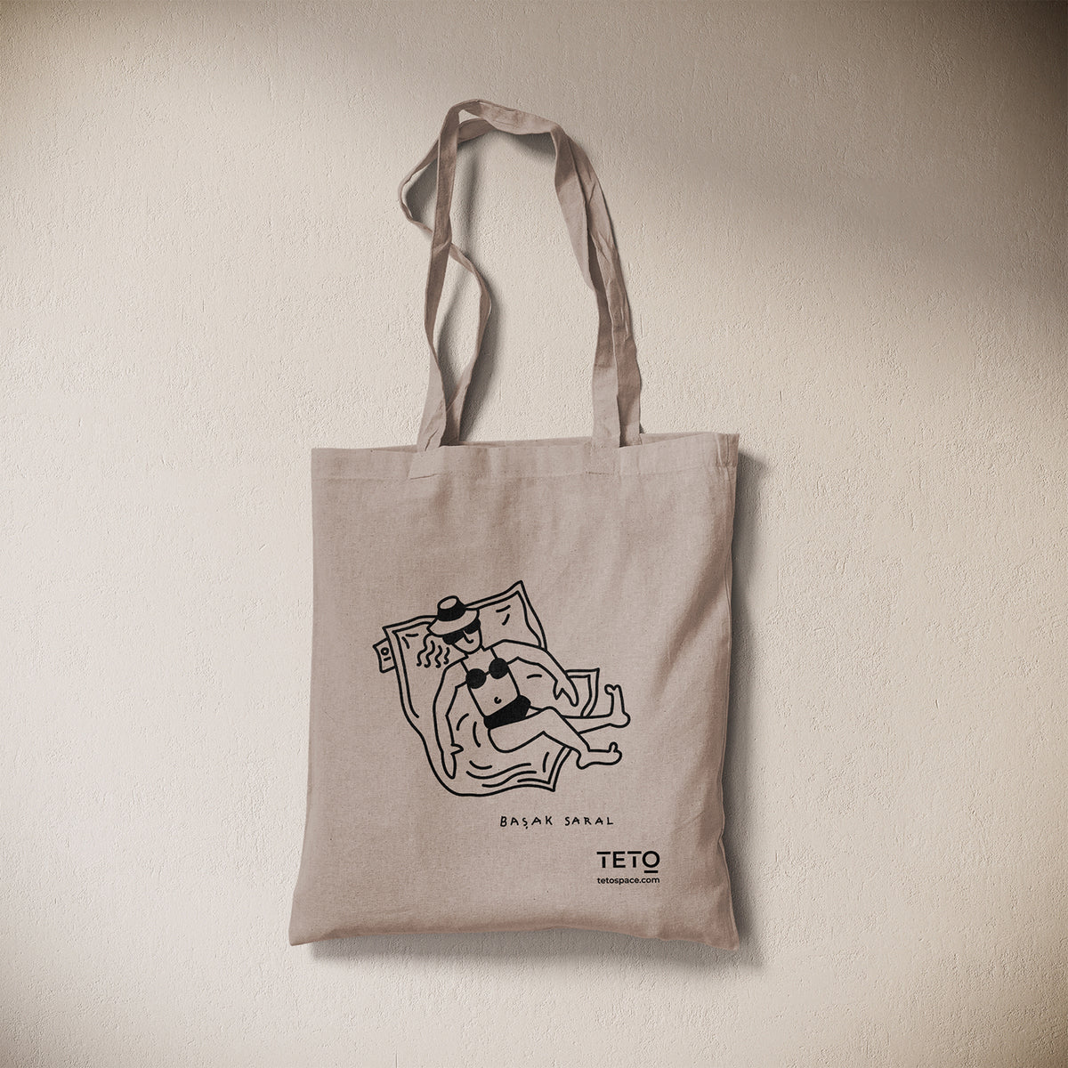 Tote bag in canvas Grigio con illustrazione Pouf di Başak Saral (donna che prende il sole sdraiata sul pouf), vista frontale – TETO