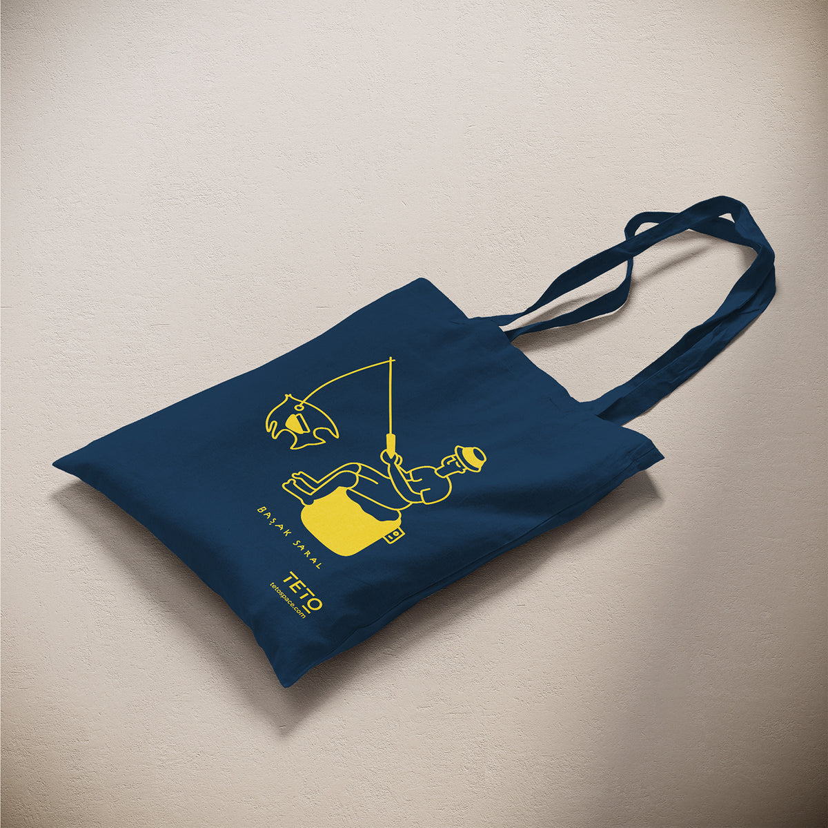 Tote bag in canvas Blu con illustrazione Fish di Başak Saral (pescatore seduto sul pouf), vista laterale – TETO