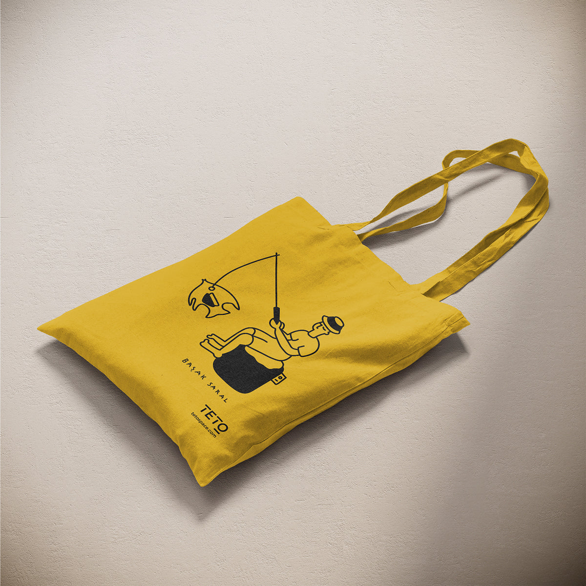 Tote bag in canvas Giallo con illustrazione Fish di Başak Saral (pescatore seduto sul pouf), vista laterale – TETO