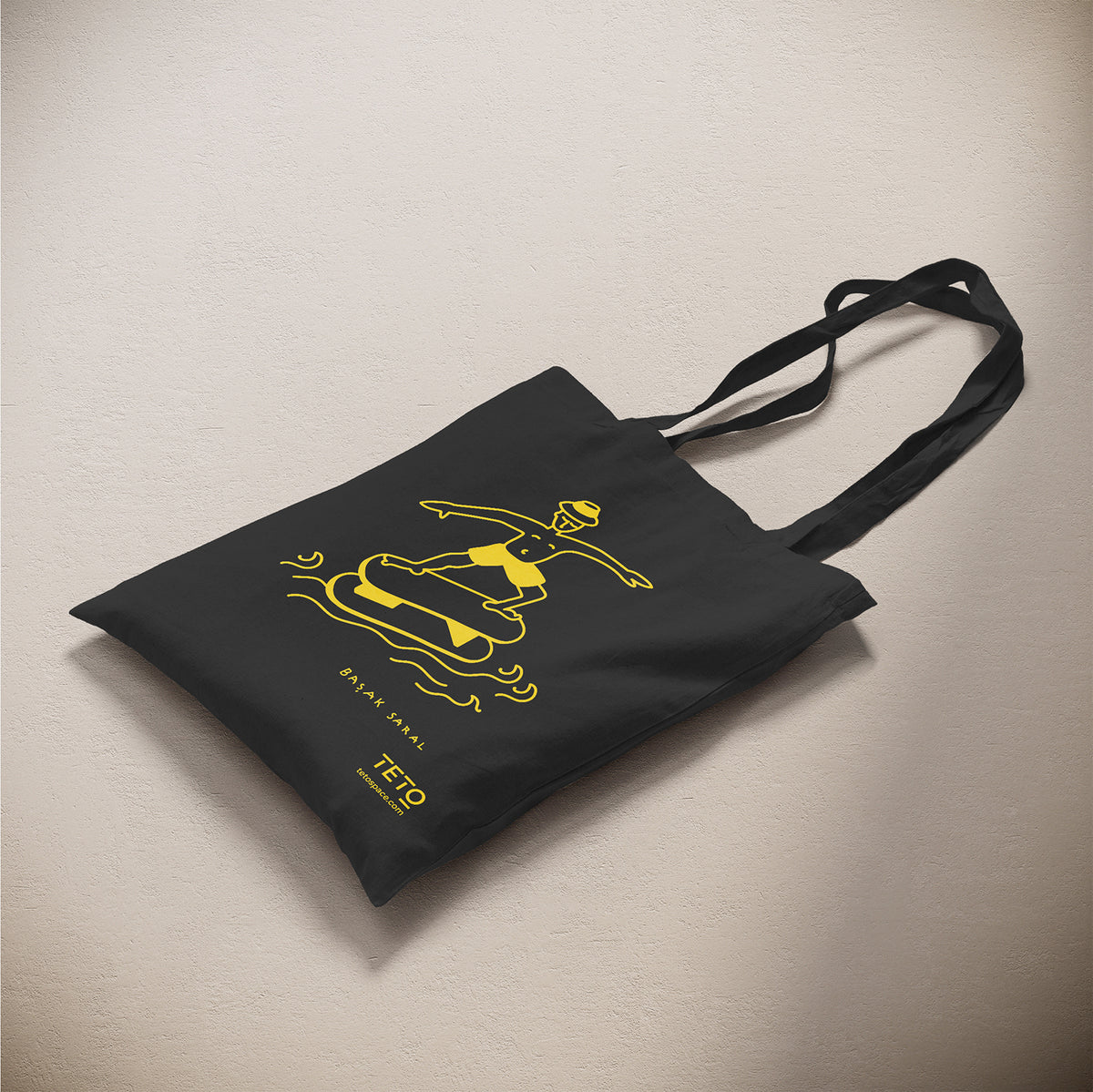Tote bag in canvas Nero con illustrazione Serf di Başak Saral (surfista sul pouf tra le onde), vista laterale – TETO