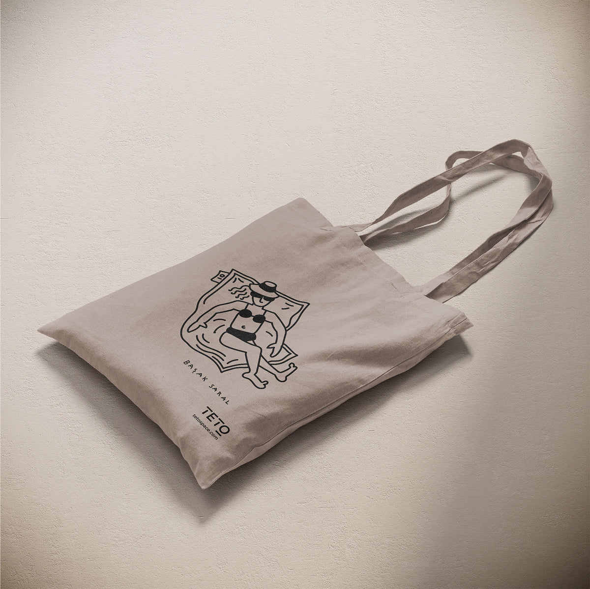 Tote bag in canvas Grigio con illustrazione Pouf di Başak Saral (donna che prende il sole sdraiata sul pouf), vista laterale – TETO