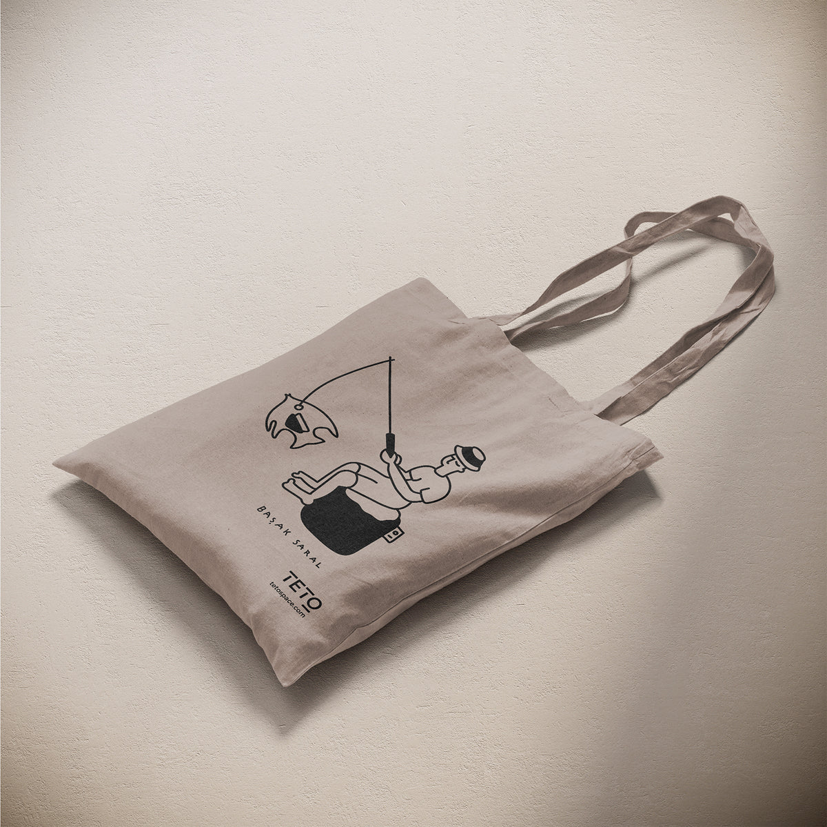 Tote bag in canvas Grigio con illustrazione Fish di Başak Saral (pescatore seduto sul pouf), vista laterale – TETO